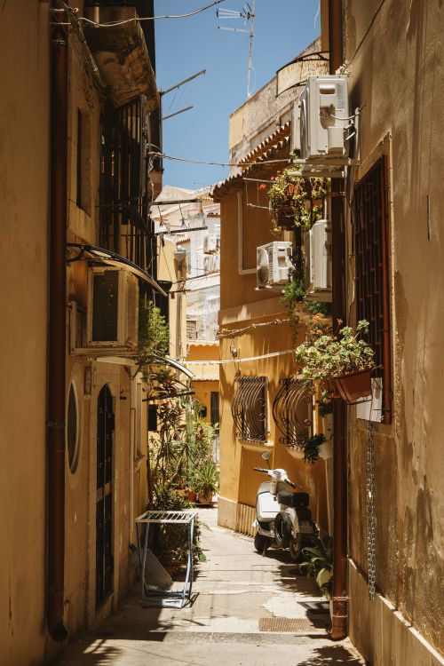 Free Picturesque Sicilian alleyway with scooter and plants under a sunny sky. Stock Photo