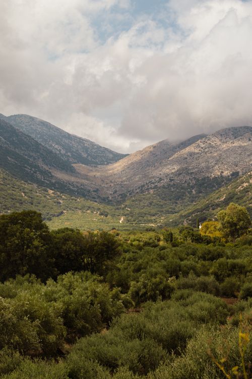 Free Beautiful landscape of lush greenery and majestic mountains under a cloudy sky in Greece. Stock Photo