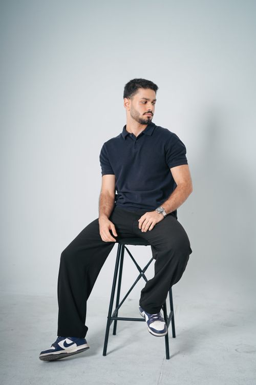 Free A male model in casual wear sitting on a stool in a studio setting. Stock Photo