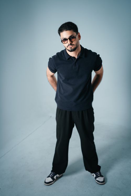 Free Young male model in casual attire posing confidently in a modern studio environment. Stock Photo