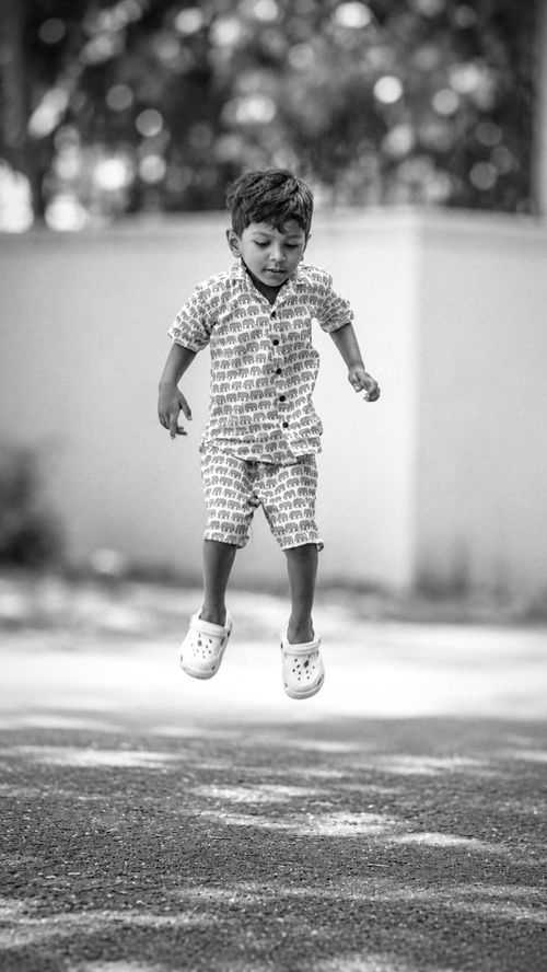Free A young child enjoying a playful moment, captured in mid-air in a black and white setting. Stock Photo