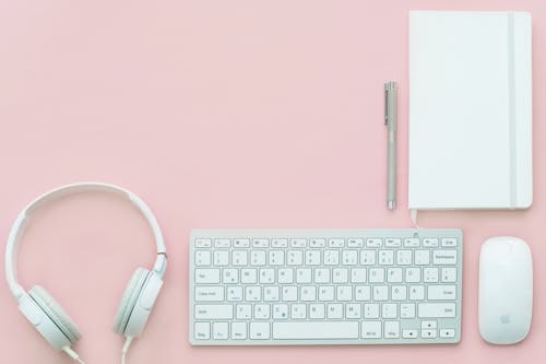 Free Apple Compact Keyboard, Magic Mouse, and Corded Headphones on Pink Surface Stock Photo