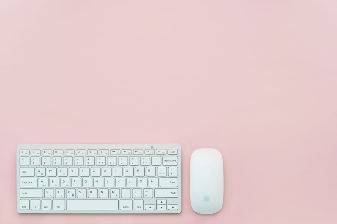 Free A clean and minimalist flat lay of a white keyboard and mouse on a pastel pink background. Perfect for feminine office themes. Stock Photo