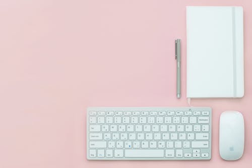 無料 ピンクの表面にシルバーのアップルキーボードとマジックマウス 写真素材