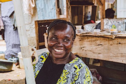 Free Smiling woman in a vibrant outfit at an outdoor market setting, exuding warmth and happiness. Stock Photo