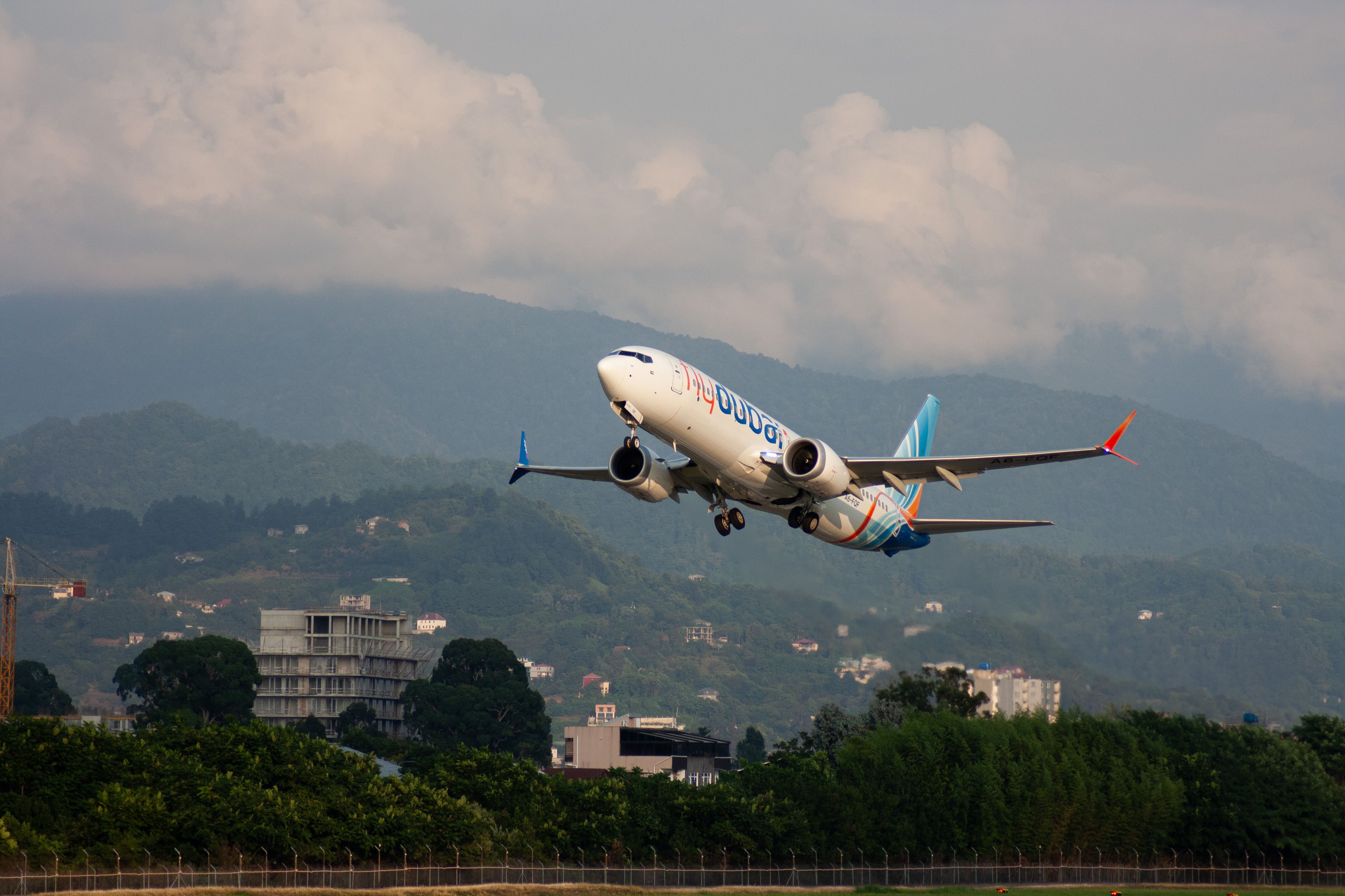 A Flydubai aircraft takes off from Batumi airport against a scenic mountain backdrop. — flights from Minsk to Batumi