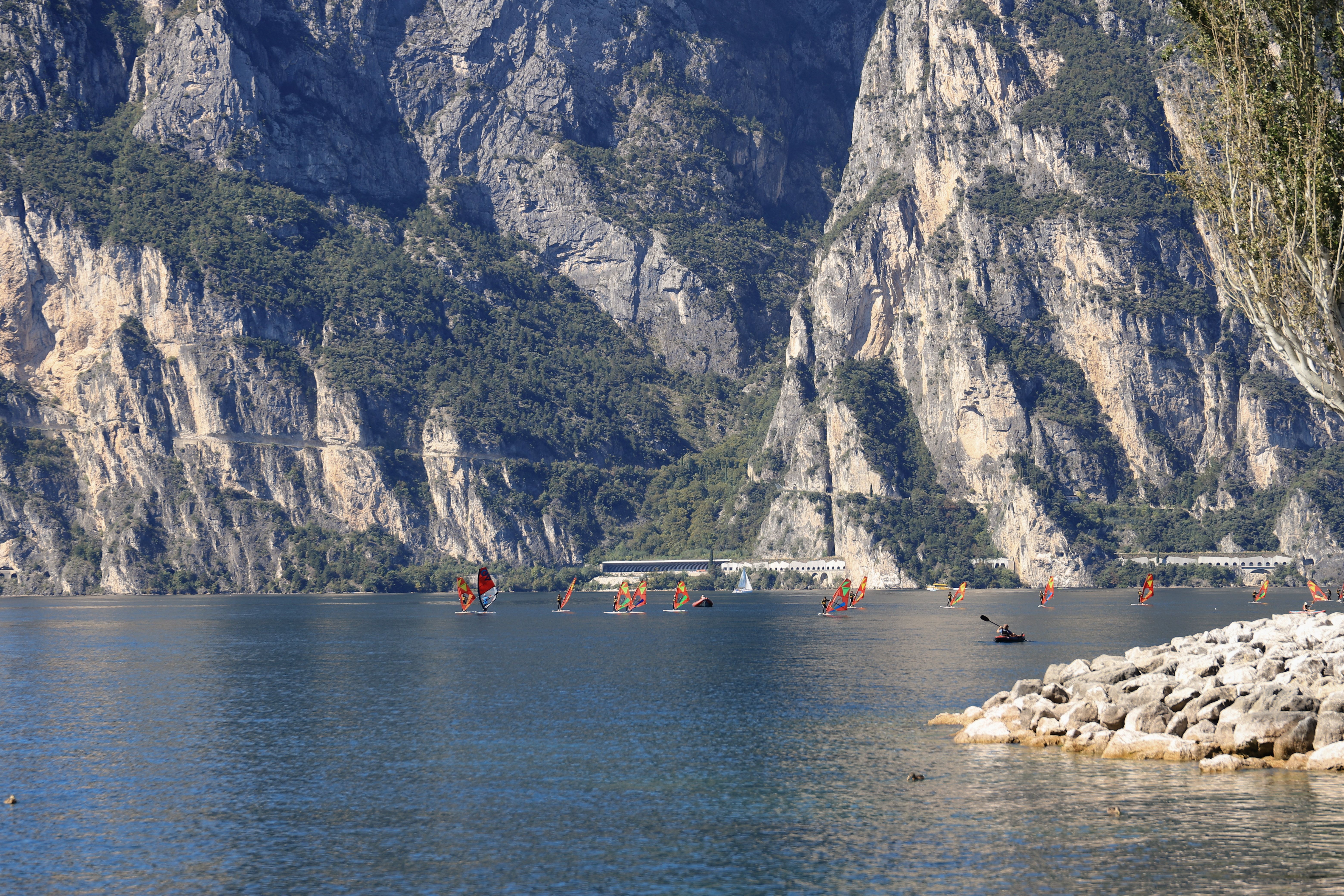 A scenic view of Torbole and windsurfing on Lake Garda with towering mountains in the background.