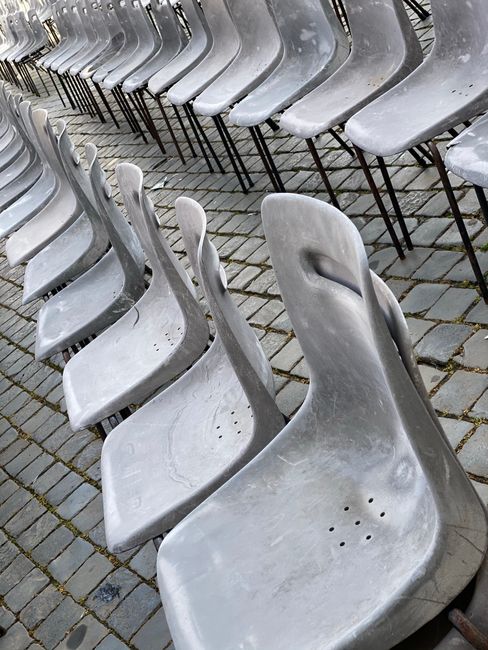 Rustic outdoor arrangement of worn plastic chairs on stone pavement.