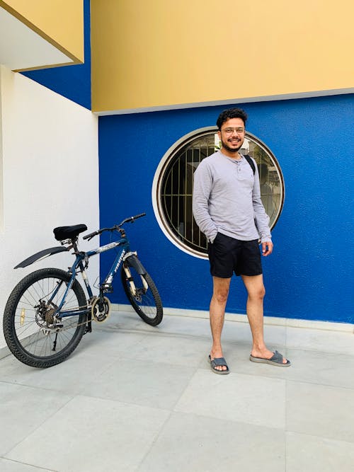 Man in Gray Long Sleeves Shirt Standing Beside Black Bicycle