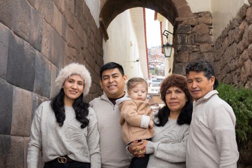 Free A family of five embraces in a historic alleyway, capturing a mix of ages and generations. Stock Photo