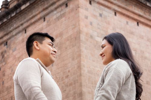 Free A couple sharing a joyful moment outdoors, in front of a brick building. Stock Photo
