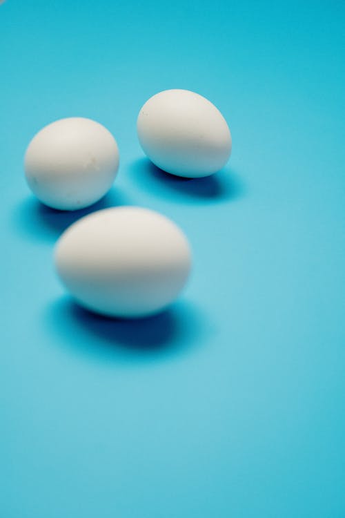 3 White Eggs on Blue Surface