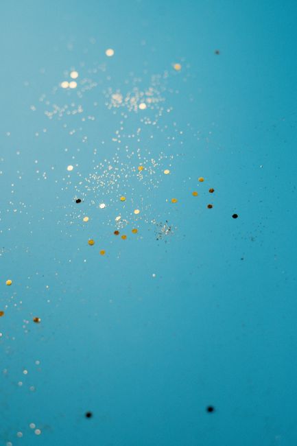 Enchanting vertical shot of gold glitter sparkles on a vibrant turquoise backdrop, perfect for artistic designs.