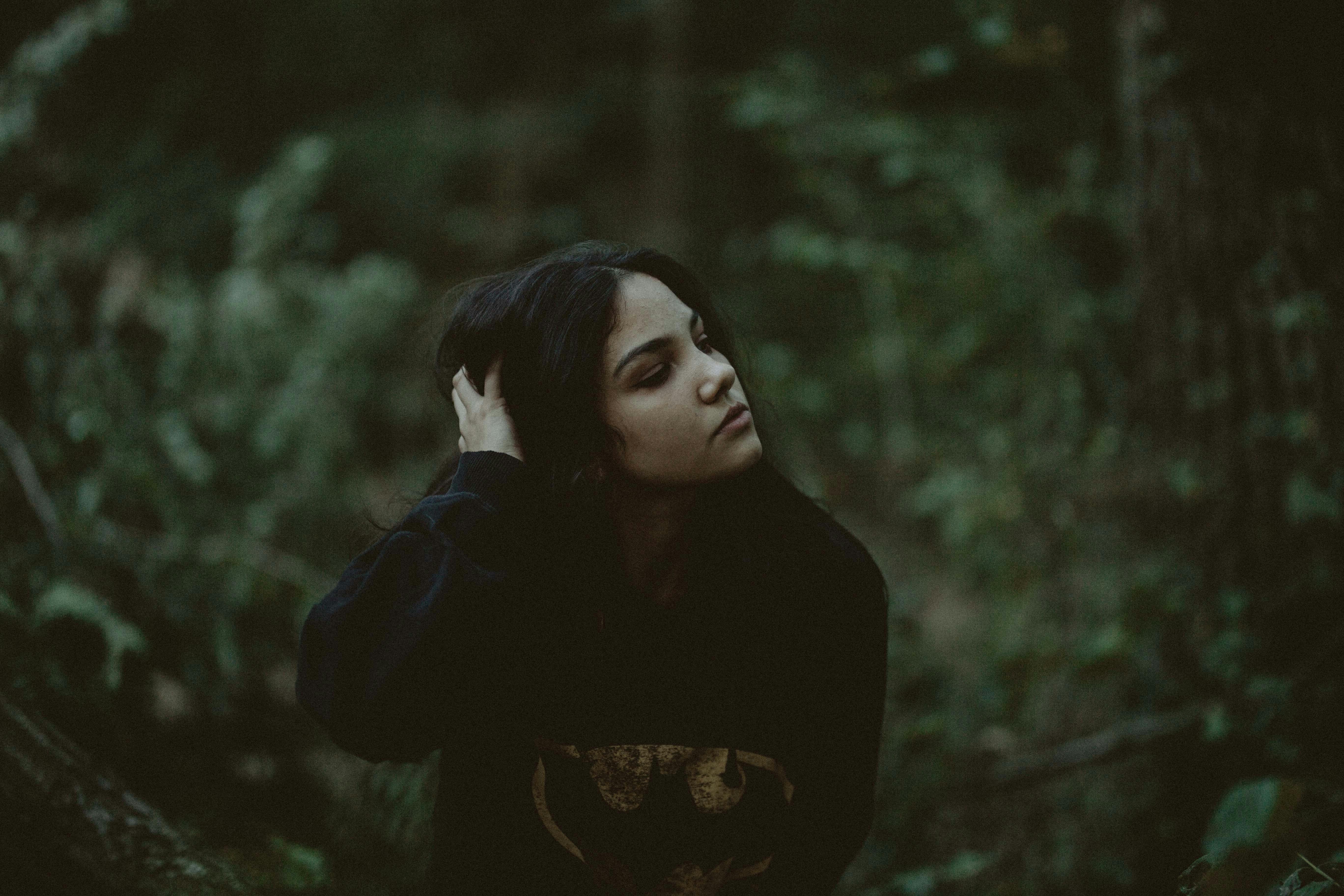 一幅描绘女人在黑暗森林中沉思的肖像，传递出深度和内省