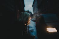 一张女人在昏暗的城市街道上吸烟的忧郁照片