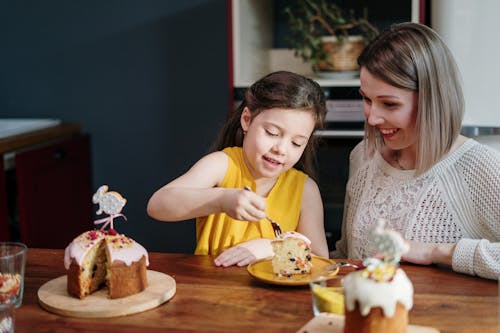 Free Mom and Daughter Eating Cake on Brown Wooden Table Stock Photo