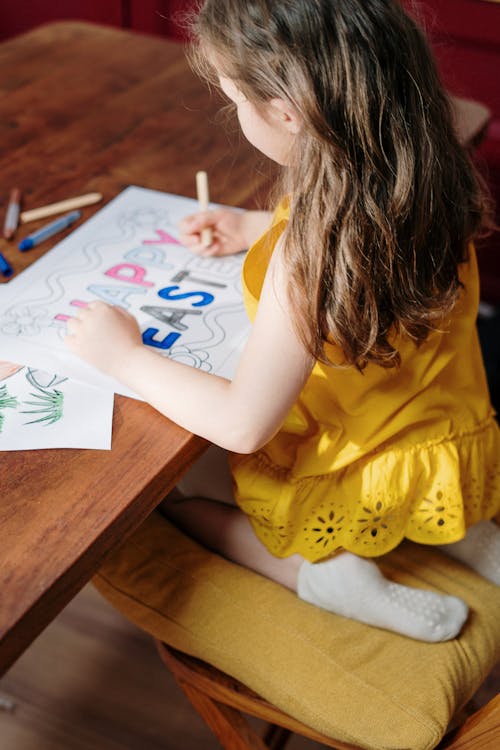 Free Girl in Yellow Shirt Drawing on White Paper Stock Photo