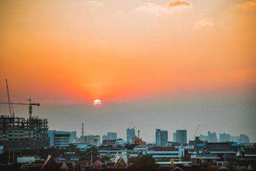Free Stunning Bangkok skyline with cranes and a warm sunset over the city. Stock Photo