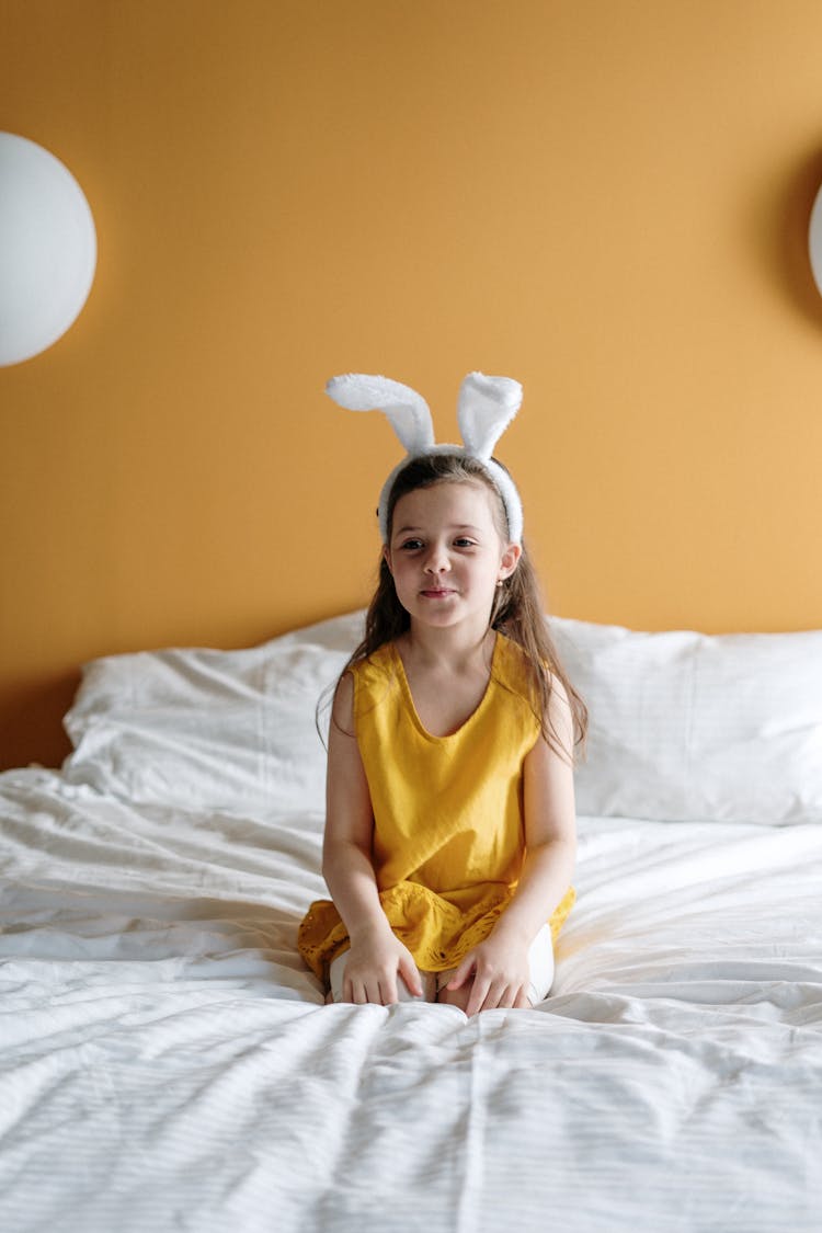 Girl In Yellow Top Sitting On Bed