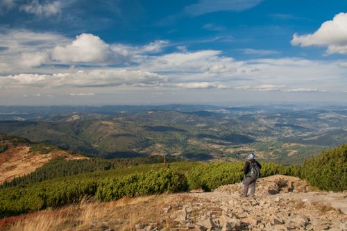 Free A hiker enjoys a panoramic view of the Beskid Mountains in Poland under a bright blue sky. Stock Photo