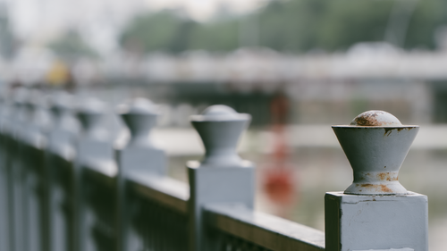 Free Close-up of a rusty metal fence near a river, with blurred background. Stock Photo