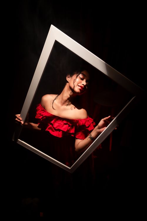 Free Creative portrait of a woman framed against a dark background, wearing a vibrant red dress with dramatic lighting. Stock Photo