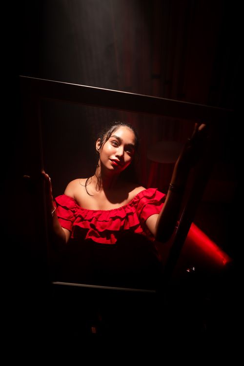 Free Artistic portrait of a woman in a red dress with dramatic lighting and shadows. Stock Photo