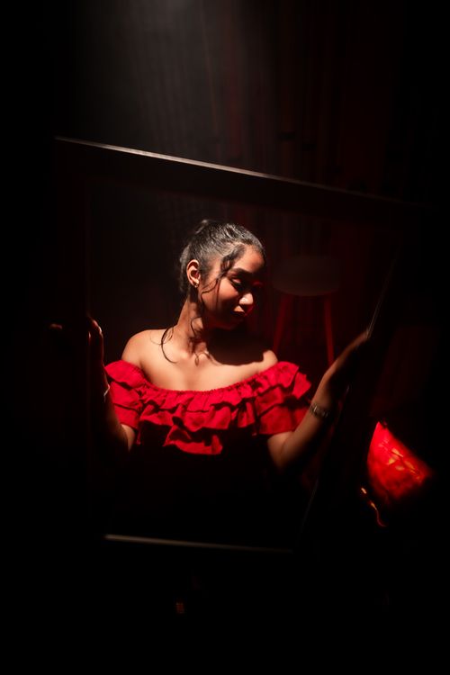 Free Captivating portrait of a woman in a red dress, highlighting dramatic lighting and reflection. Stock Photo