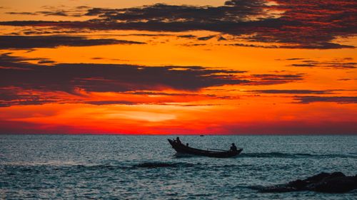 Free A fishing boat sailing at sunset over Cửa Tùng Beach, Vietnam, with a vibrant sky. Stock Photo