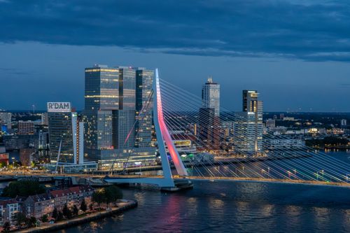 Free Aerial view of Erasmus Bridge and Rotterdam skyline illuminated at dusk. Stock Photo