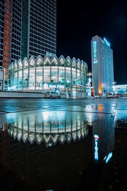 Free A stunning night view of Warsaw's modern architecture reflected in water, featuring the Novotel hotel and Bank Polski building. Stock Photo