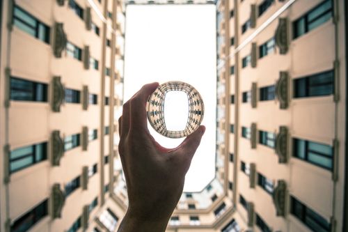 Free Hand holding glass ball reflecting unique Warsaw courtyard architecture with a modern twist. Stock Photo