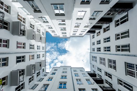 Dramatic view of a Warsaw apartment courtyard looking towards a blue sky.