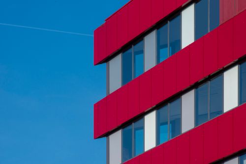 Free Diagonal view of modern red building facade with windows against clear blue sky in Bergschenhoek, Netherlands. Stock Photo