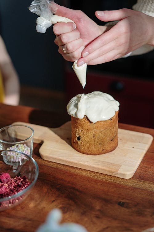 Person Holding Piping Bag with White Icing