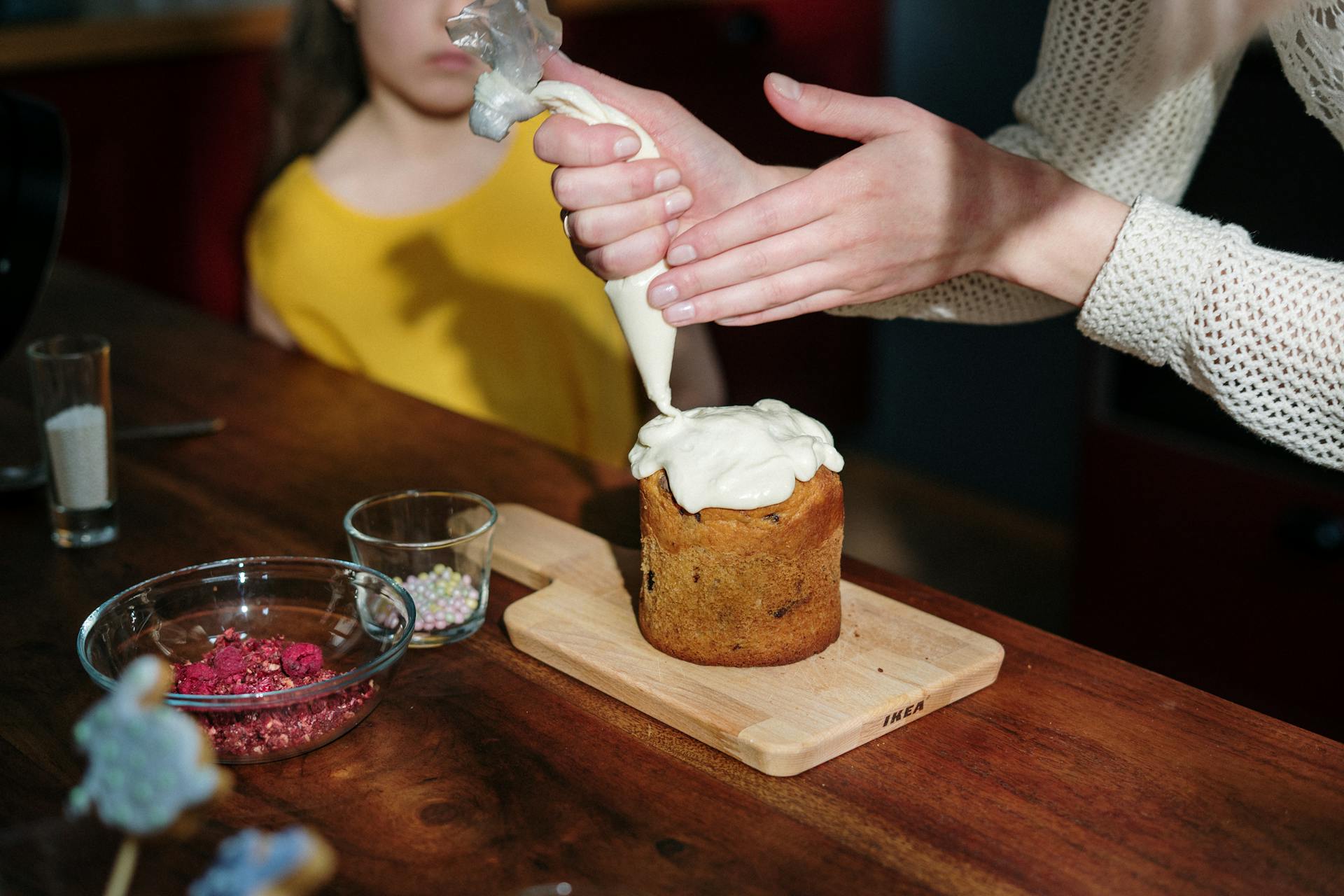 A mother and daughter adorably decorate an Easter cake at home, enjoying family time together.