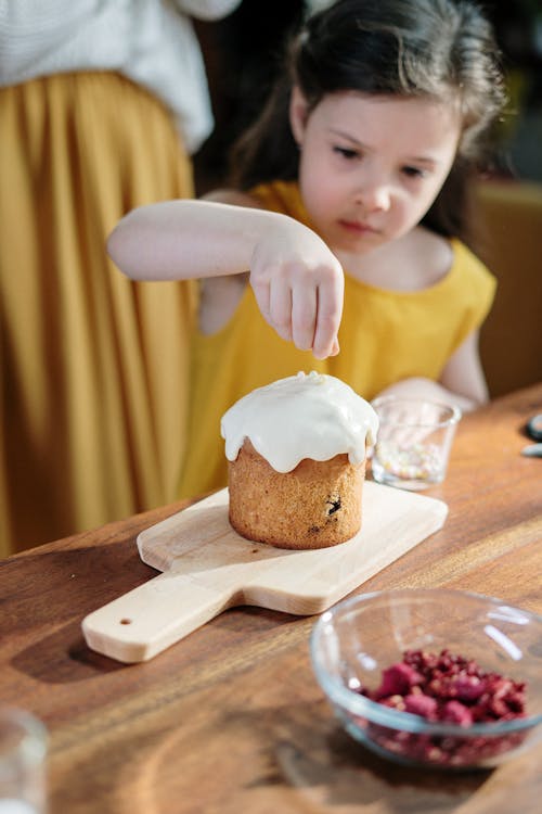 Child in Yellow Shirt Decorating a Cake