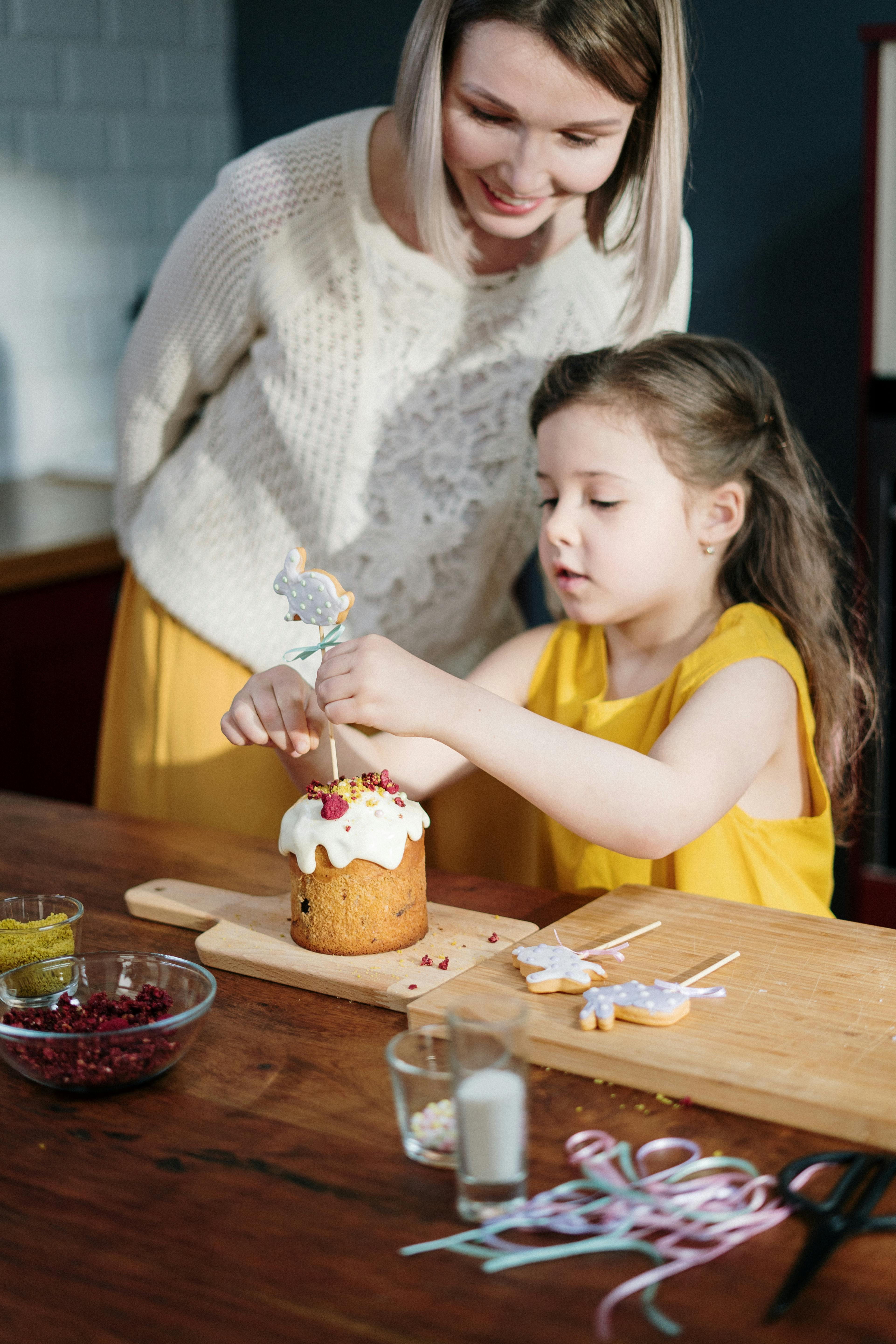 girl in yellow shirt decorating a cake on brown wooden table