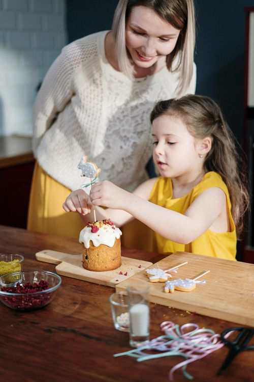 Free A mother and daughter bond over decorating a homemade Easter cake together in their kitchen. Stock Photo