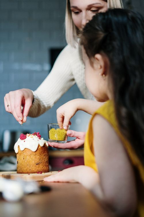 Free A lovely moment of mother and daughter bonding while decorating an Easter cake in a cozy kitchen. Stock Photo