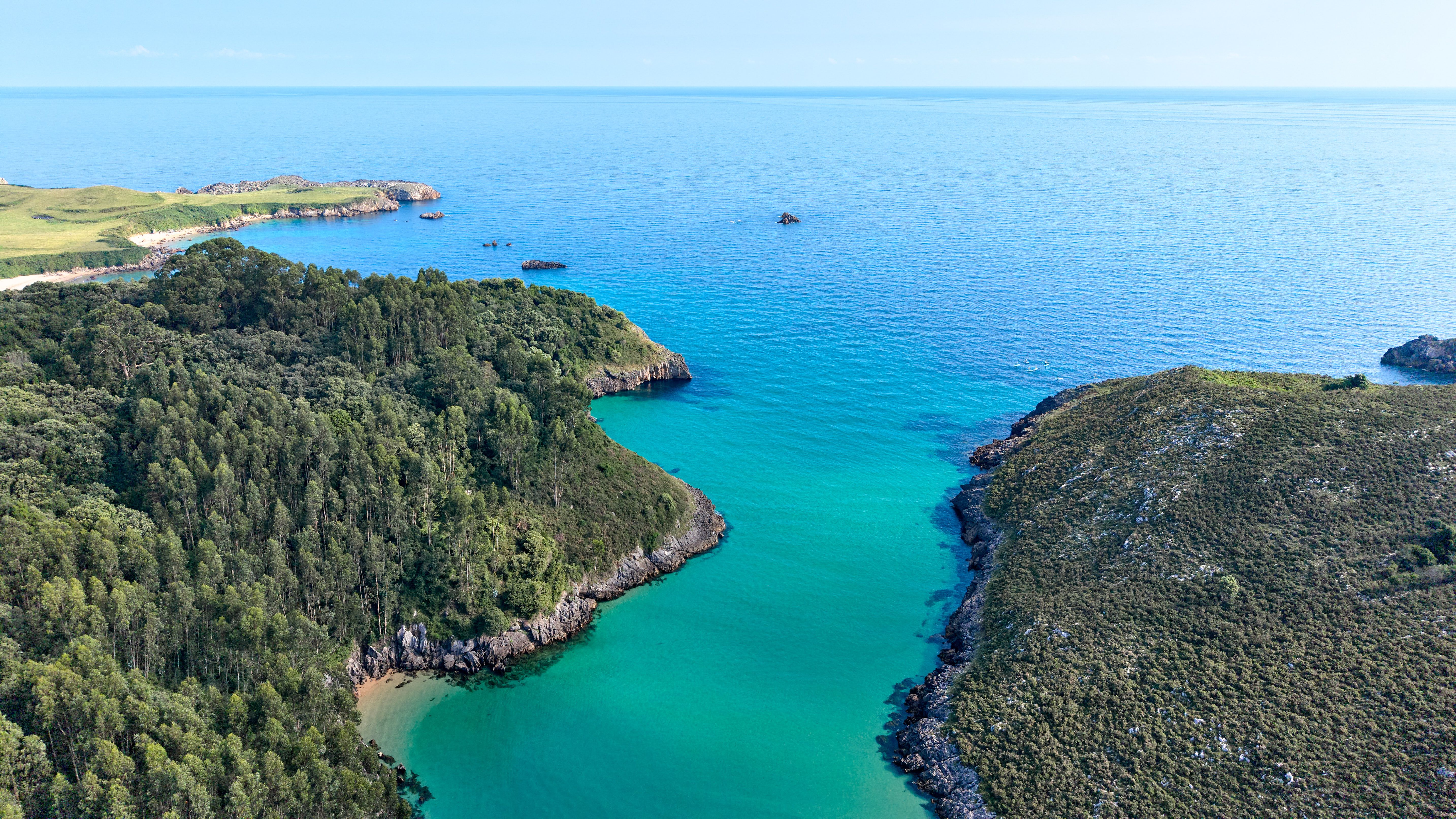 Serene aerial view of the lush coastline of Asturias, Spain with turquoise waters.
