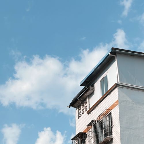 Free A white building with barred windows against a bright, clear blue sky on a sunny day. Stock Photo