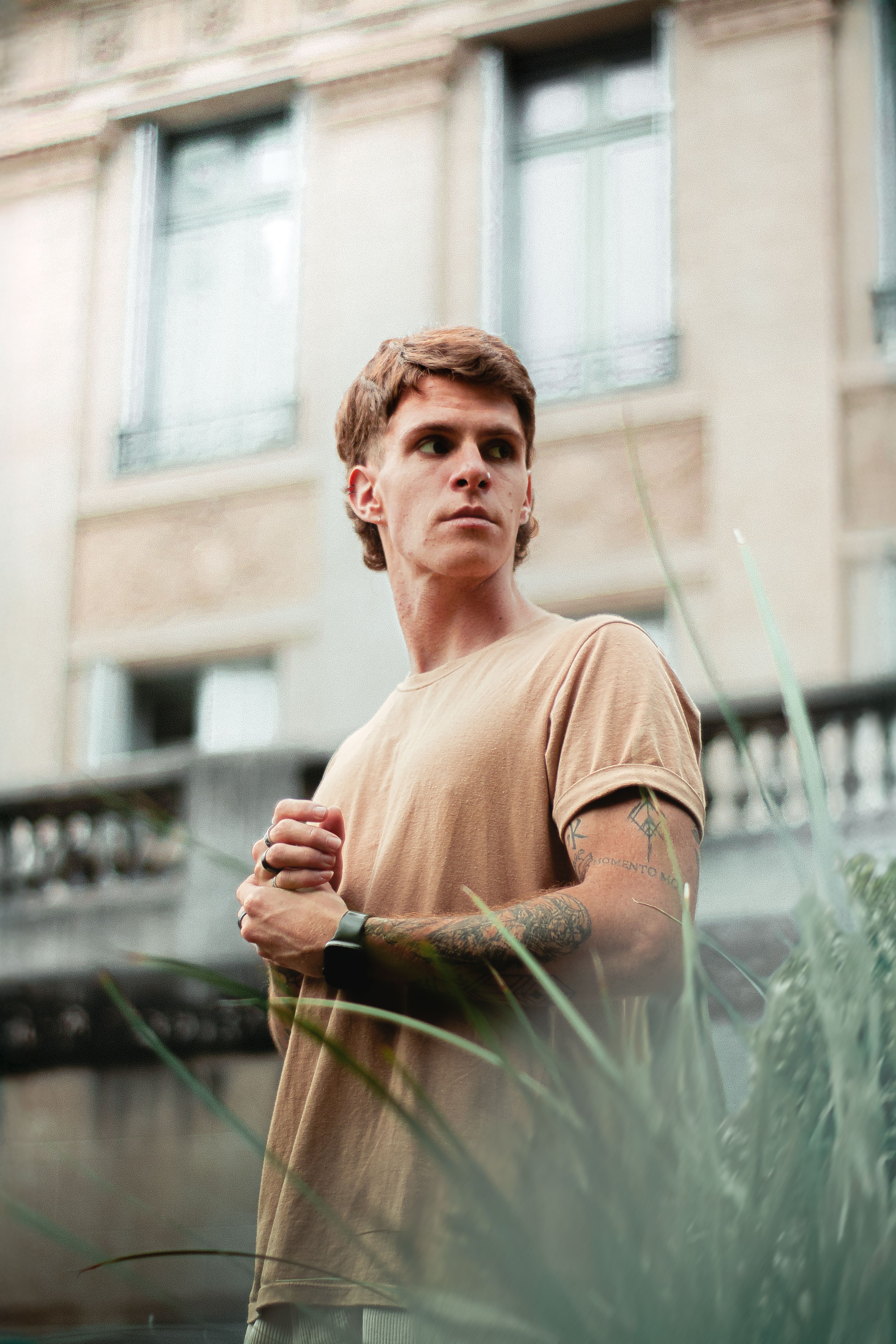Young man looking thoughtful in a city setting, captured outdoors with a vintage style.