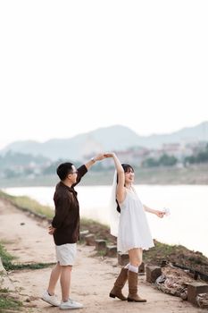 A joyful couple dances by the river in Lạng Sơn, Việt Nam, during sunset.