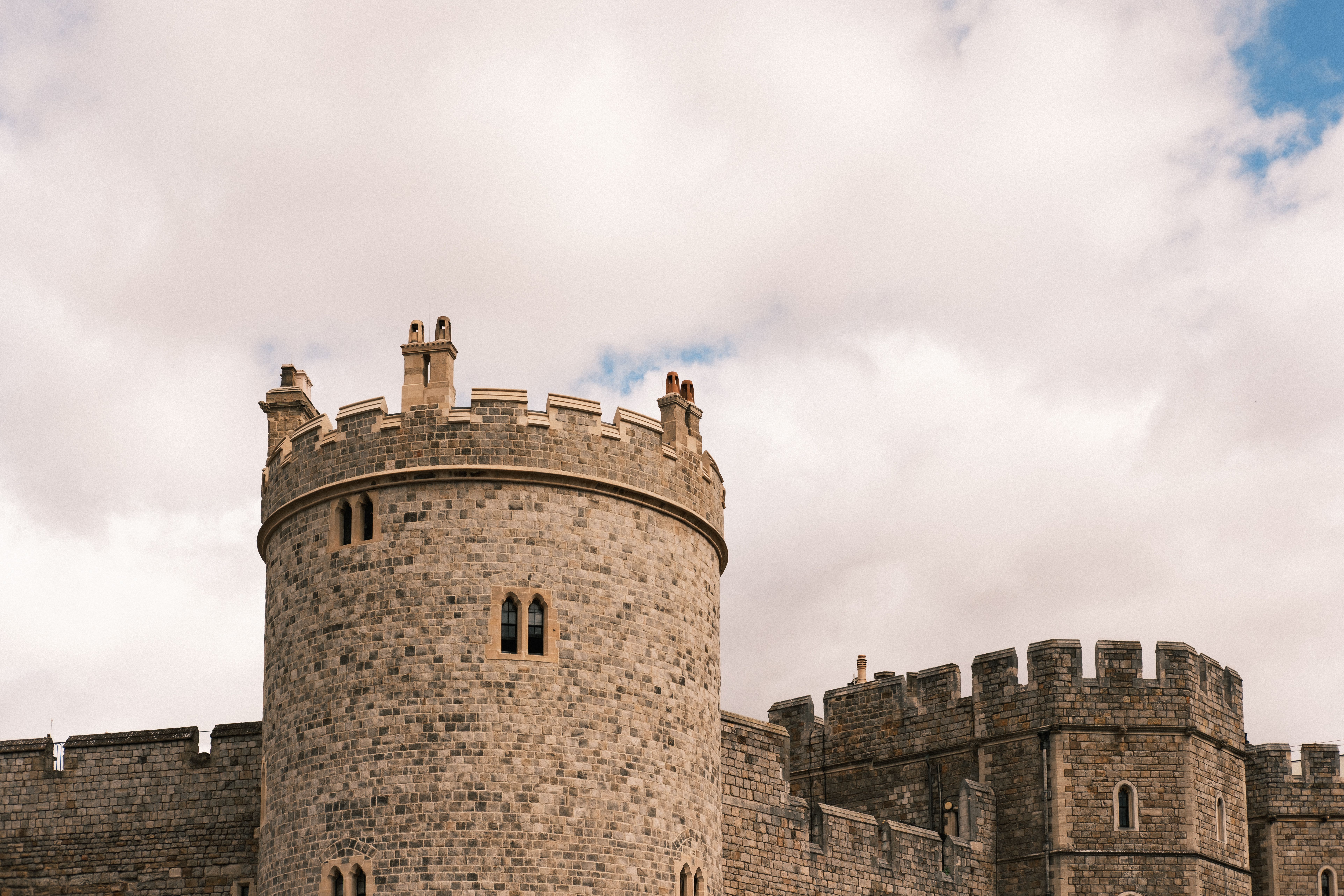 A classic view of Windsor Castle's stone tower set against a cloudy sky, showcasing its medieval architecture.