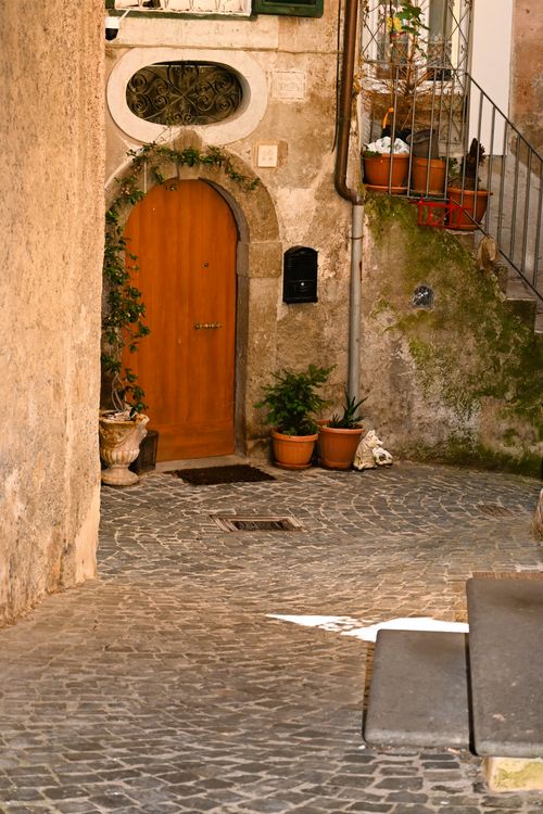 Free Picturesque cobblestone alley with plants and arch in Vignanello, Italy. Stock Photo