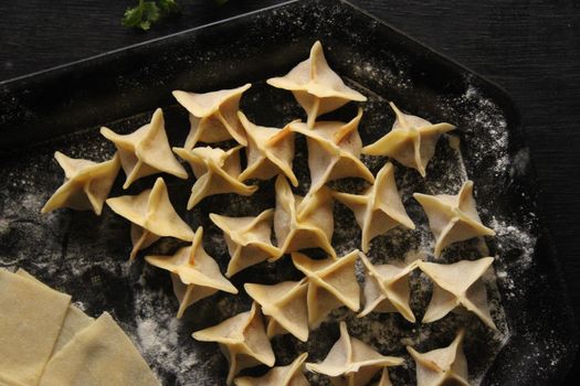 Top view of neatly arranged star-shaped dumplings on a floured baking tray, ready for cooking.