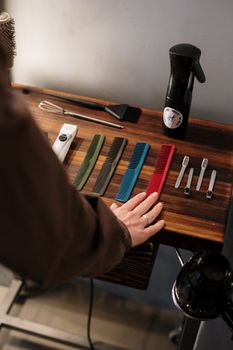 A close-up of colorful combs, scissors, and barber tools on a wooden surface in a salon.