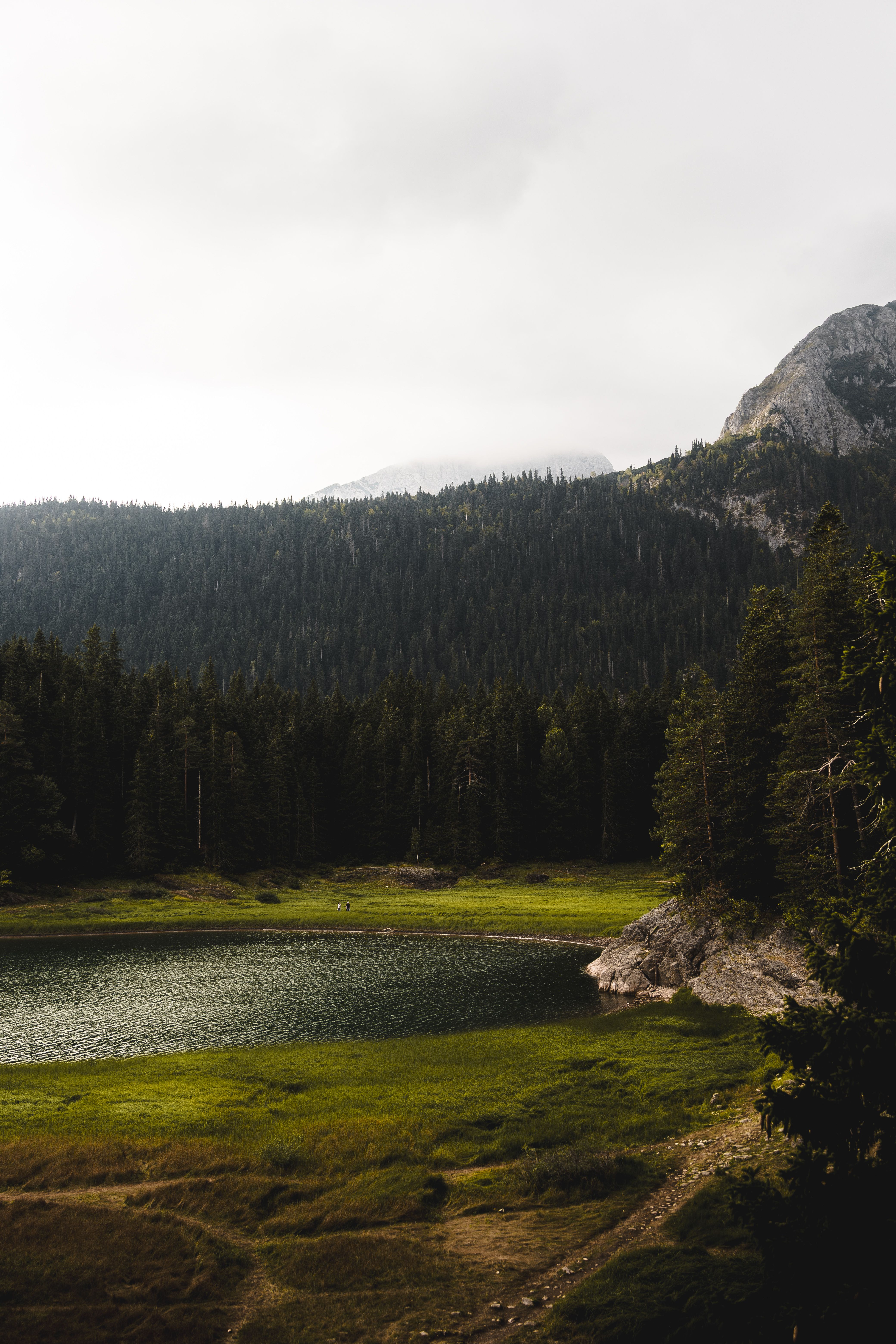 A mountain lake reflects the surrounding landscape in soft natural light.