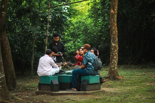 Free Group of friends having a casual meet-up in a lush park in Dhaka, Bangladesh, playing guitar and socializing. Stock Photo